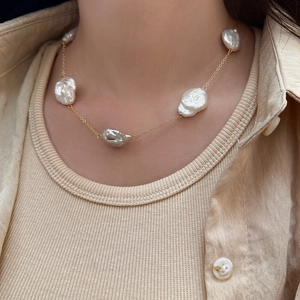 Baroque freshwater pearl necklace with gold chain shown on model in a minimalist style