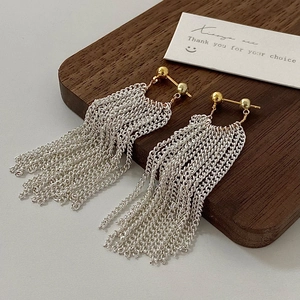 Close-up of elegant gold and silver cascading tassel earrings on a wooden stand