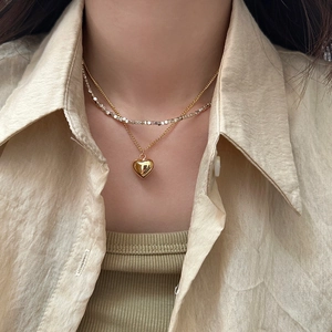 Detail of a double-layered necklace featuring a gold heart pendant and silver beads