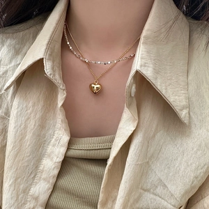 Close-up of double-layered necklace with gold heart pendant and mixed metallic silver beads