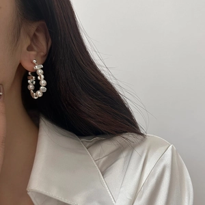 Silver drop earrings with white pearls and irregular metal blocks on a model