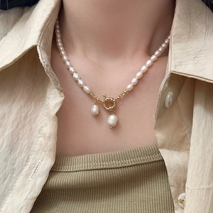 Gros plan sur un collier de perles baroques avec fermoir doré porté par un mannequin