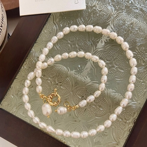 Vue détaillée du collier de perles baroques avec fermoir OT doré sur plat en verre