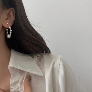 Elegant pearl earrings with silver beads shown on model wearing white silk shirt