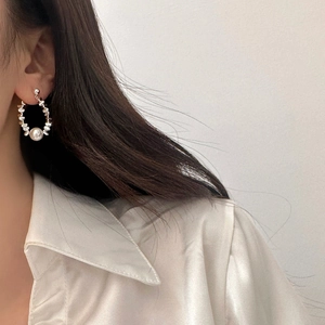 Detail of silver beaded hoop earrings with large white pearl drop on model in silk shirt