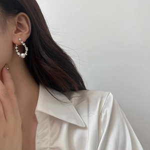 Detail of elegant silver irregular beads and white pearl earring on female model