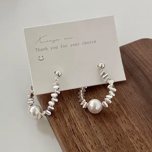 Elegant silver metallic pearl drop earrings featuring round white pearls on a display card