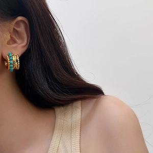 Détail de créoles dorées vintage avec perles turquoise portées par un mannequin