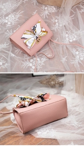 Detail view of pink lychee leather bag with elegant silk scarf bow and gold clasp