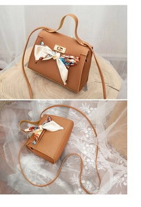 Detail of caramel lychee texture handbag with elegant printed silk scarf and gold lock
