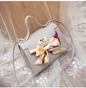 Detailed view of grey lychee pattern handbag with elegant silk scarf bow and gold hardware