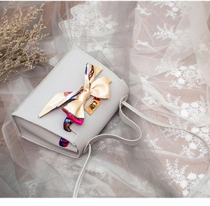 Detailed view of grey lychee leather handbag with silk scarf and gold twist lock