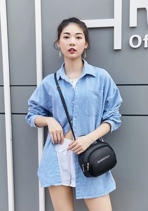 Black lychee texture mini crossbody bag with white lettering on a model outdoors