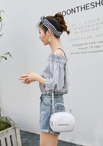 Detail of a white semi-circular mini bag with dual zippers and elegant top handle