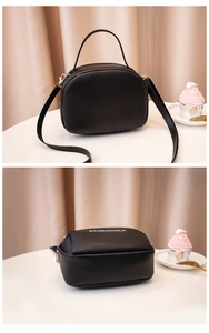 Detail of black leather handbag featuring white logo print and silver zipper hardware