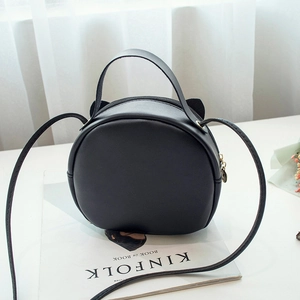 Chic black round handbag with cat ear design on white Kinfolk magazine setup