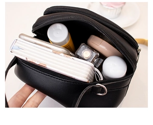 Detail view of the black multi-zippered crossbody bag showing spacious interior compartments