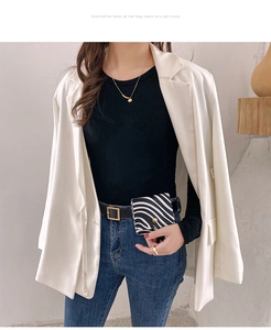 Detail of zebra pattern mini bag with gold round buckle shown on model wearing white suit