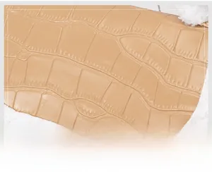 Close-up of beige crocodile pattern faux leather with white plush trim and fine stitching