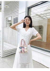Chic pink PVC crossbody bag with silk scarf detail and white lace dress in a cafe setting