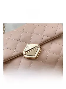 Close-up of golden polygon hardware lock on light pink quilted crossbody chain bag