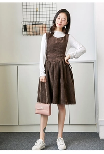 Detail of coffee corduroy overall dress with pleats and a matching pink chain handbag