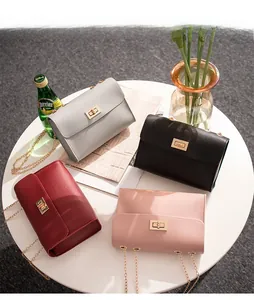 Detail view of chain crossbody bags in four colors with gold twist locks on a table