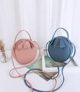 Detail of round mini handbags in pink and blue pebbled leather with gold metal logo