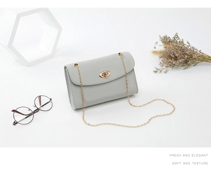 Détail du sac à bandoulière en cuir gris-bleu avec chaîne dorée et fermoir pivotant