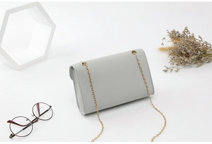 Sac minimaliste en cuir gris clair avec bandoulière chaîne dorée et rabat structuré