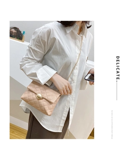 Detail of quilted crossbody bag featuring a golden diamond lock and metal chain strap
