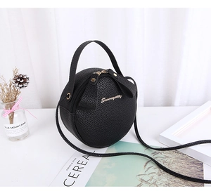 Close-up of black round crossbody bag showing litchi grain texture and gold logo