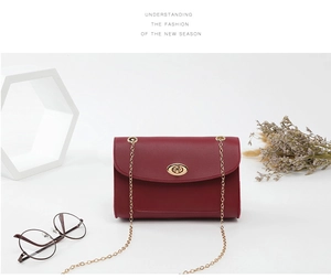 Détail du sac à bandoulière en cuir grainé rouge avec fermoir doré et bandoulière chaîne