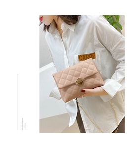 Detail of nude quilted leather texture with gold geometric metal clasp and chain strap