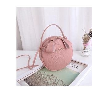 Close-up of pink round bag with lychee texture leather and rabbit ear zipper detail