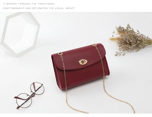 Détail du sac bandoulière bordeaux avec fermoir doré rotatif et texture de cuir