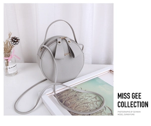 Detailed macro view of gray pebbled leather round bag with bunny ear zipper pulls