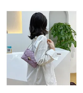 Detail of lavender quilted chain bag featuring a gold twist lock and elegant crossbody strap