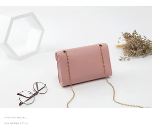 Détail d'un sac bandoulière en cuir rose avec chaîne dorée dans un décor élégant et chic