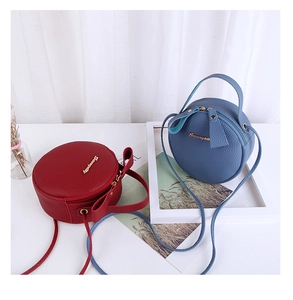 Detail of round pebble leather crossbody bags in red and blue with gold hardware