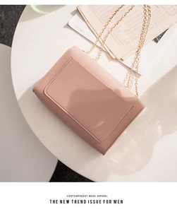 Detailed view of pink leather crossbody bag with stitching and gold chain strap