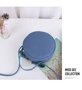 Detail of round pebble leather crossbody bag in fog blue with metallic zipper closure