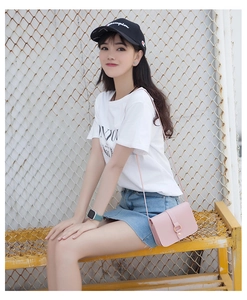 Side view of pink leather crossbody bag with golden ring buckle on a female model