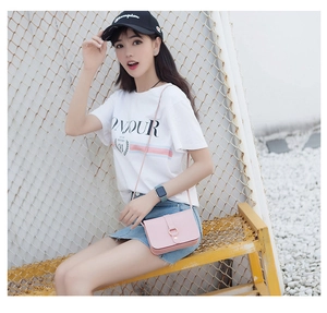 Detail of light pink mini leather crossbody bag with metal ring buckle on summer outfit