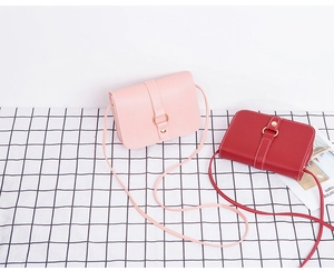 Detailed shot of pink and red rectangular crossbody bags with metal buckle on plaid background