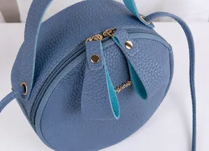 Detail of smooth double metal zippers on blue litchi pattern leather round crossbody bag