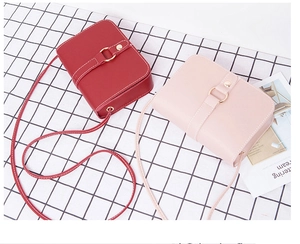 Detailed view of red and pink mini crossbody bags with metallic buckle on plaid background