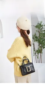 Fashionable black crocodile embossed crossbody bag featuring a classic gold square buckle