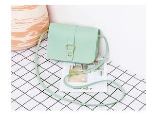Detail of mint green cross-body bag with pebble grain faux leather and gold ring buckle