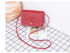 Detail of red leather square crossbody bag featuring gold ring accent and snap closure